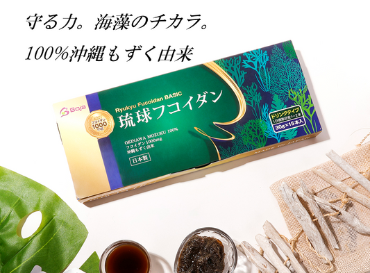 琉球フコイダンのパッケージとモズク海藻、白い木の枝の健康食品イメージ